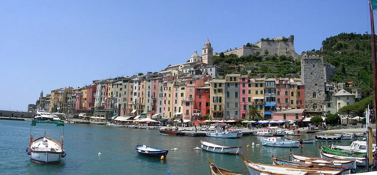 Vista panoramica di Portovenere dal mare con il Castello Doria, la Chiesa di San Pietro e le case medievali colorate
