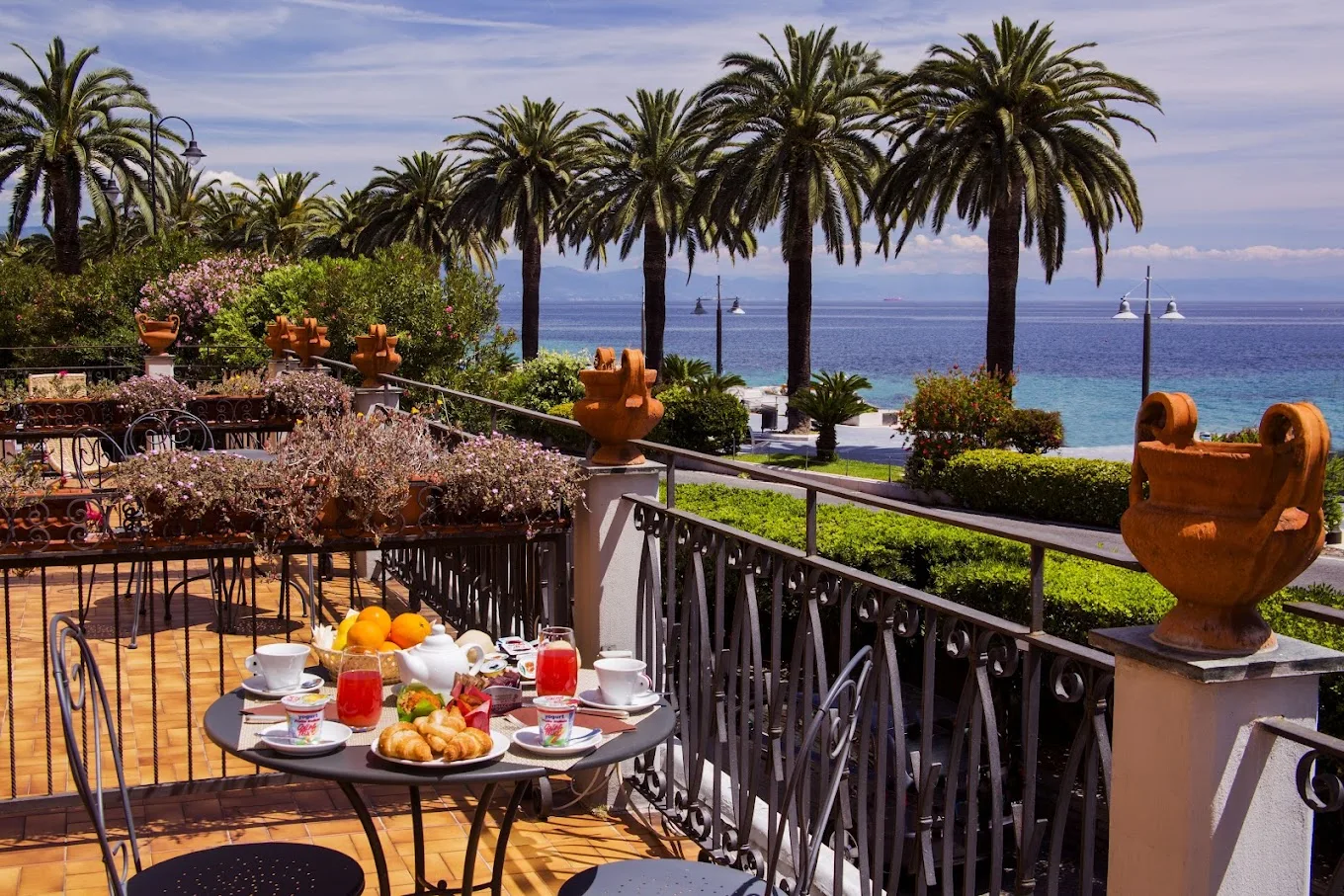 La terrazza dell'Hotel Miramare con tavoli, palme e vista diretta sul golfo di Noli