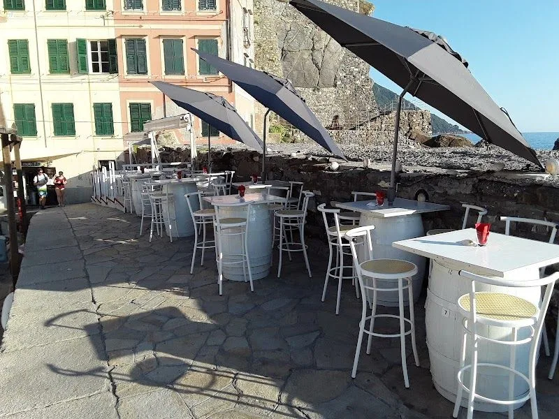 I tavoli di Al Molo 16 sul porticciolo di Camogli, con le case colorate e le barche sullo sfondo