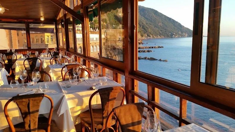 La veranda del ristorante La Camogliese a picco sul mare di Camogli, con i tavoli apparecchiati e la vista sulla costa