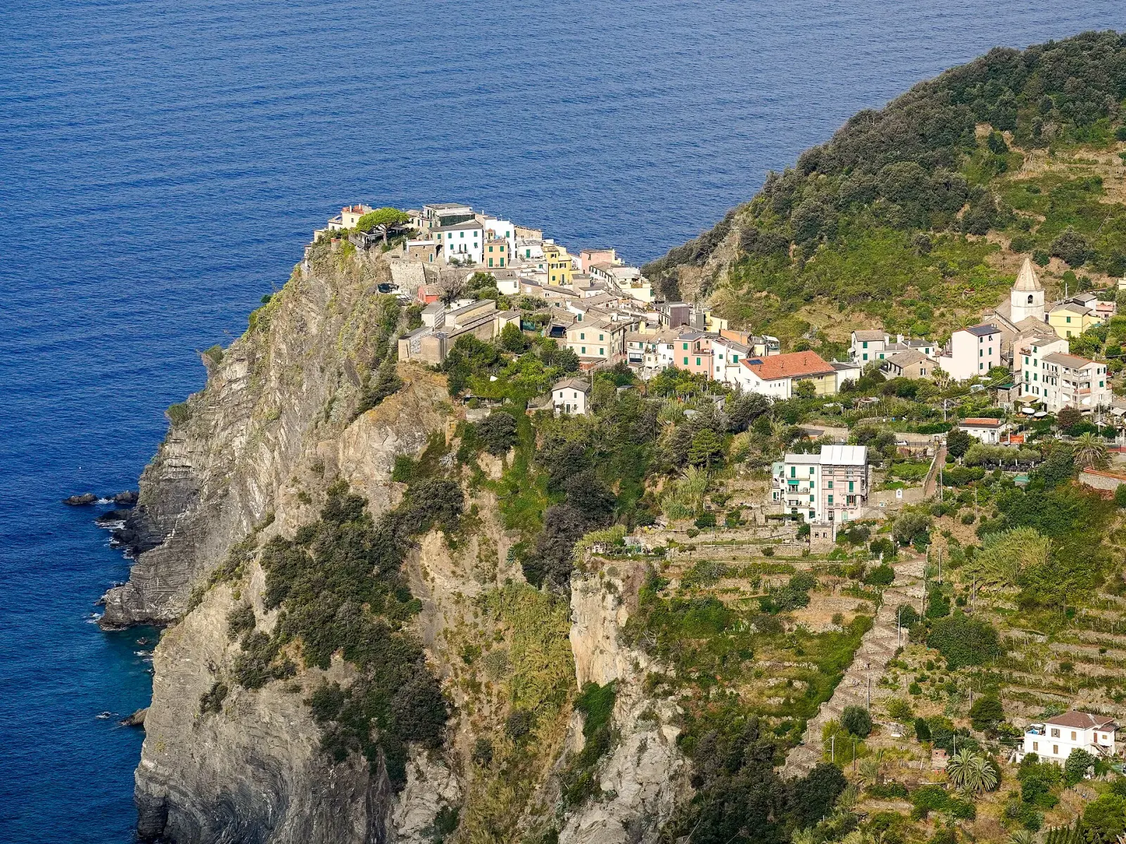 Corniglia vista dall'alto: il borgo sul promontorio tra i vigneti terrazzati e il mare delle Cinque Terre
