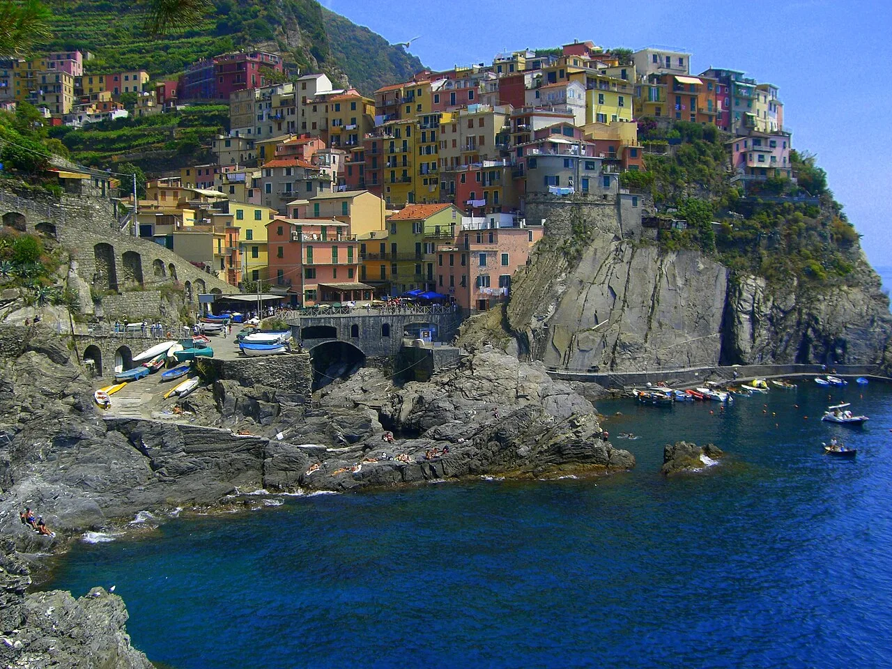 Panorama di Manarola da nord, case colorate affacciate al mare e il porto