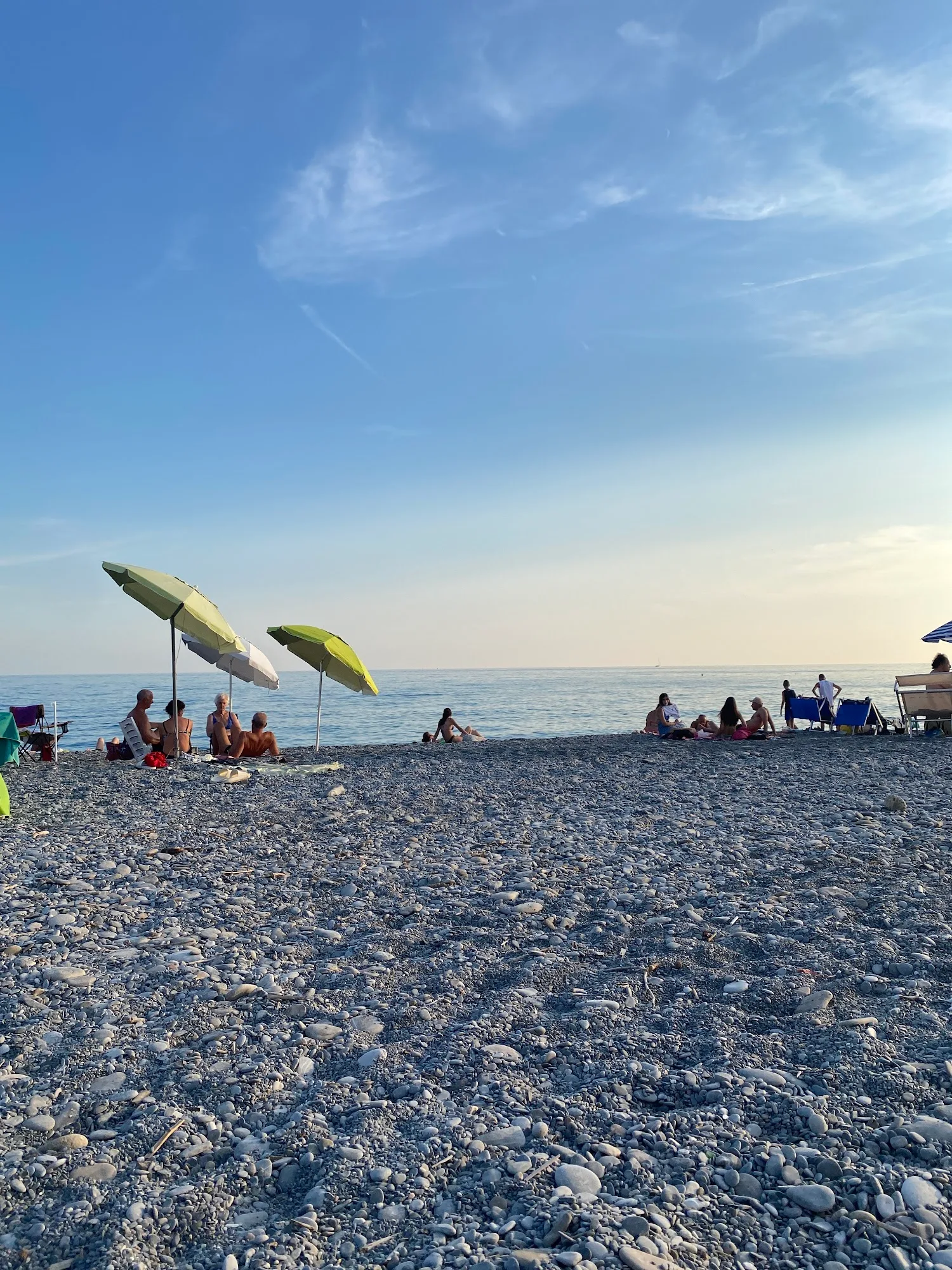 La spiaggia di Bordighera al tramonto, con i ciottoli, il mare e le palme lungo il lungomare