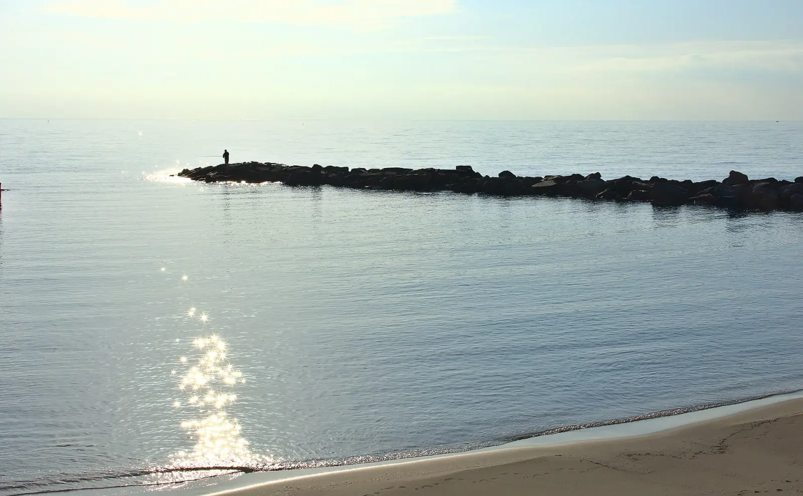 Tratto di spiaggia a Sanremo con la riva e l'acqua del mare in primo piano
