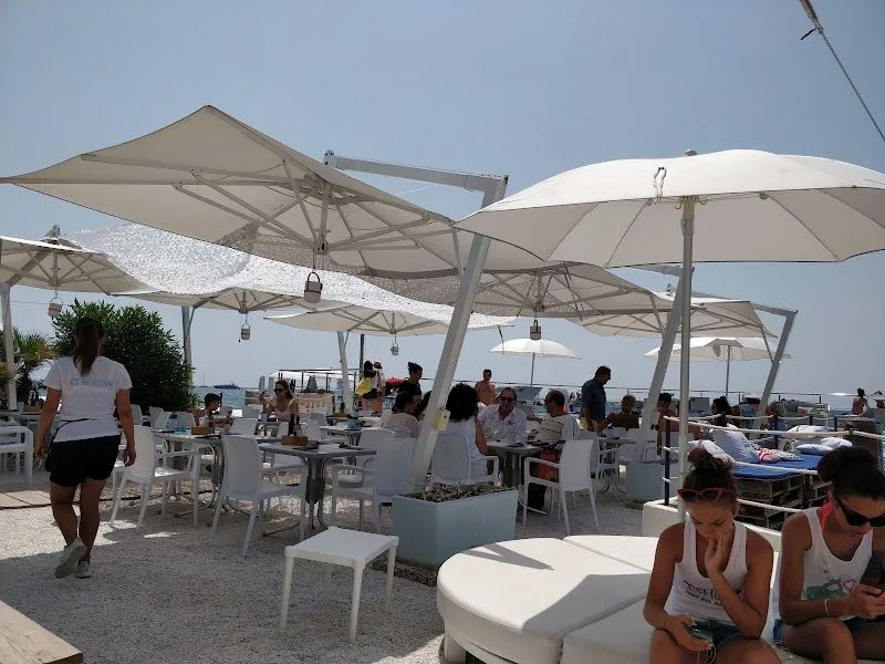 La spiaggia Tre Ponti di Sanremo, con la sabbia, il mare blu e le colline sullo sfondo