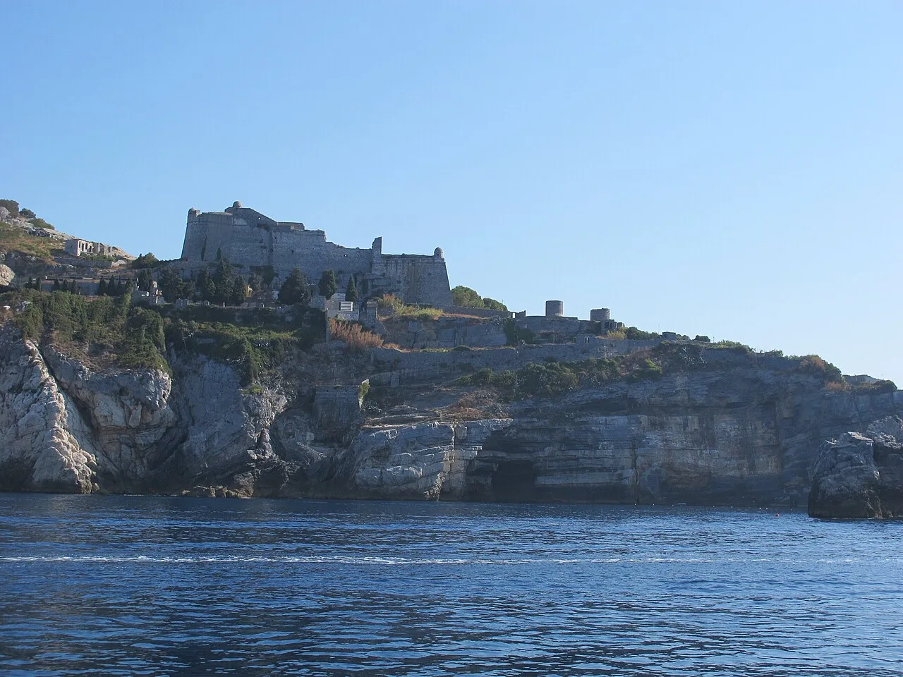 La Grotta di Byron a Portovenere vista dall'acqua: pareti rocciose scure e mare verde intenso sotto il promontorio di San Pietro