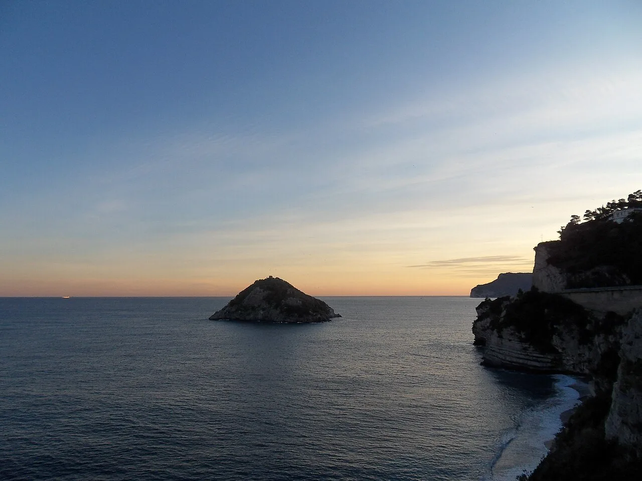 L'Isola di Bergeggi al tramonto, con le falesie della costa sulla destra