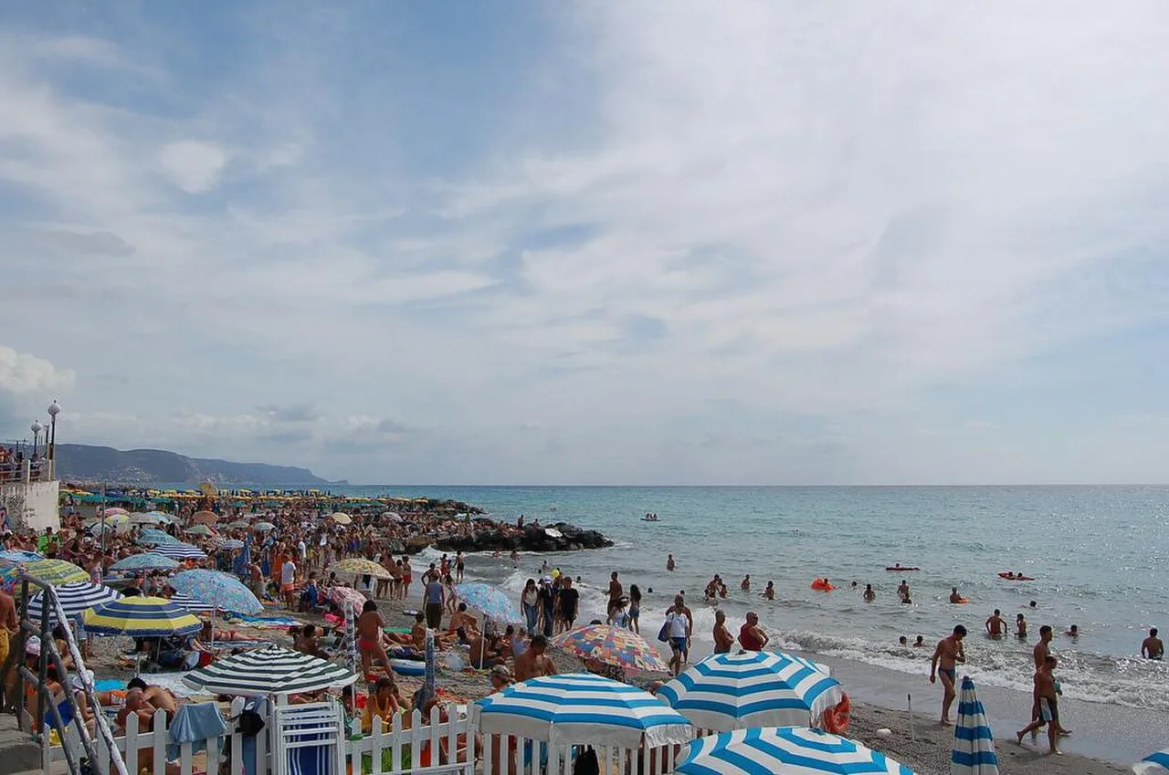 La spiaggia di Loano con ombrelloni e sabbia fine, vista verso il mare ligure in agosto