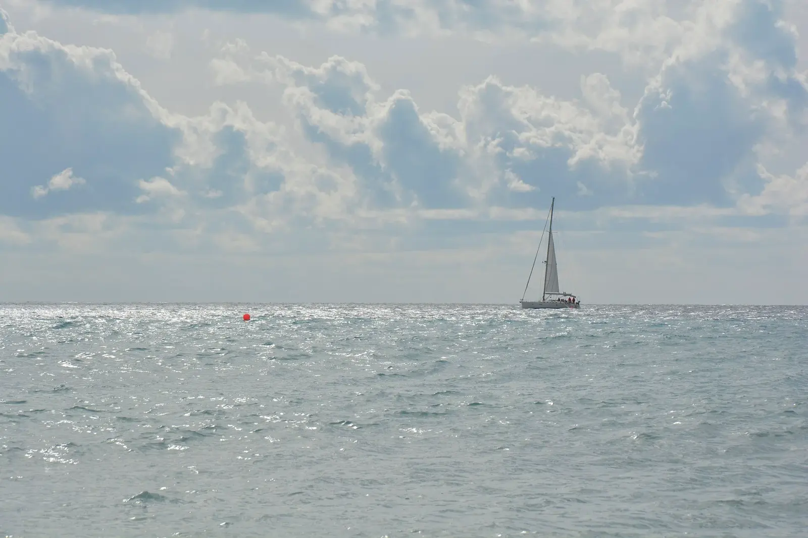 La costa di Pietra Ligure vista dal mare: la spiaggia e il Mar Ligure con qualche barca a vela all'orizzonte