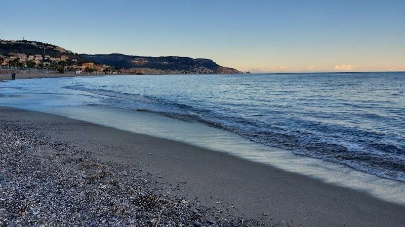 La spiaggia libera di ponente a Pietra Ligure, con la sabbia e gli scogli laterali verso il confine con Loano