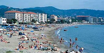 L'arenile di Vado Ligure visto dal lungomare, con sabbia e ghiaia chiara e il mare calmo