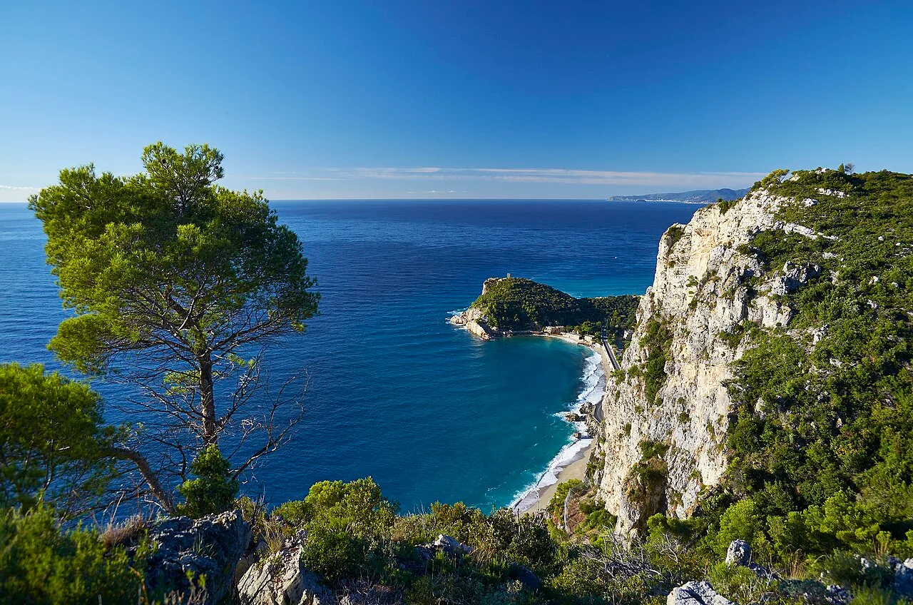 Le falesie calcaree sopra la Baia dei Saraceni viste dalla spiaggia, con il mare turchese in primo piano